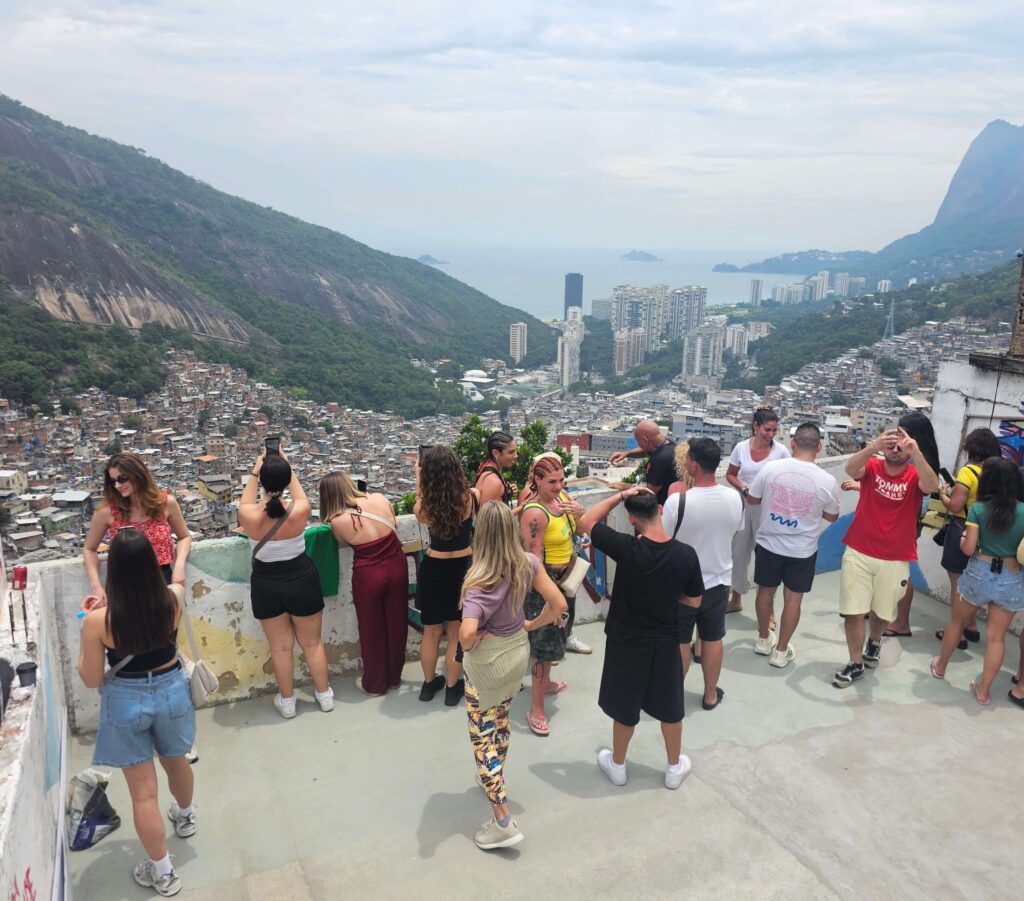 Turistas em passeio guiado pela Favela da Rocinha no Rio de Janeiro com vista panorâmica da cidade.
